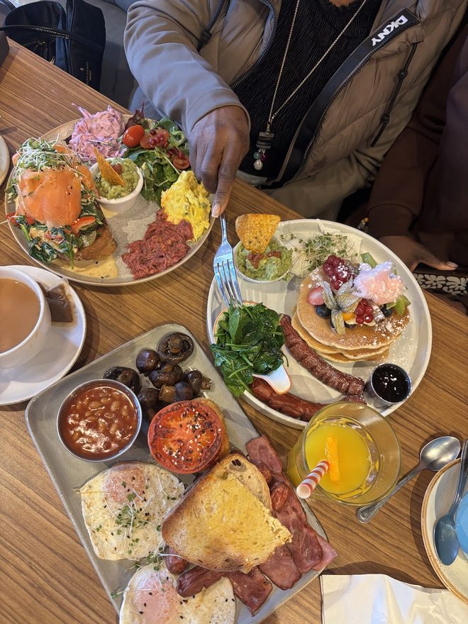 Overhead of a big shared brunch spread with platters, pancakes, coffee and juice
