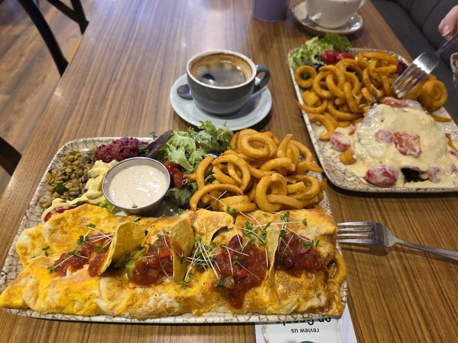 Flatbread boards and curly fries on a cafe table with a cappuccino