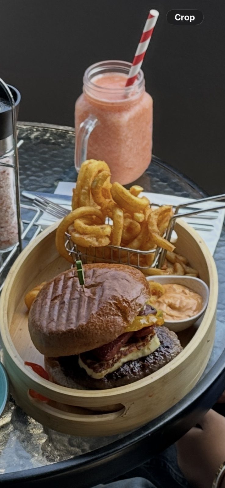 Stacked burger with curly fries and a pink milkshake